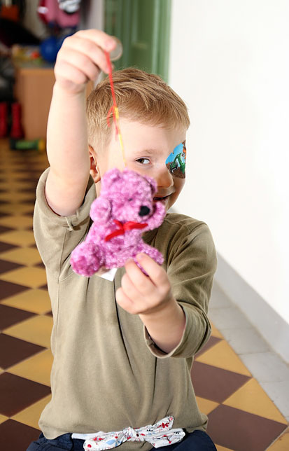 Ein Junge zeigt seinen kleinen, pinken Teddybär